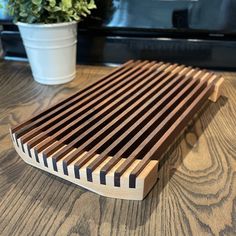 a wooden slat sitting on top of a table next to a potted plant