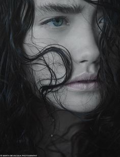 a woman with long black hair and blue eyes is shown in this artistic portrait photo