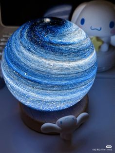 a blue and white ball sitting on top of a wooden stand next to a laptop