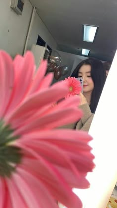 a woman taking a selfie in front of a pink flower