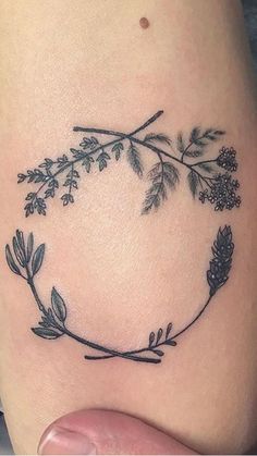 a small tattoo on the side of a woman's leg with leaves and berries