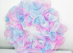 a pink and blue mesh wreath sitting on top of a white table next to a wall