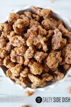 a white bowl filled with walnuts on top of a wooden table and text overlay reads salty side dish