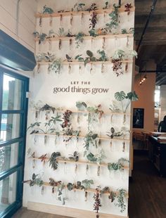 the wall is decorated with flowers and plants on wooden sticks that are hanging from it's sides