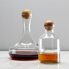 two decanters sitting next to each other on a white counter top, one with an egg in it