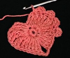 a crochet flower with a hook in the middle on a black tablecloth