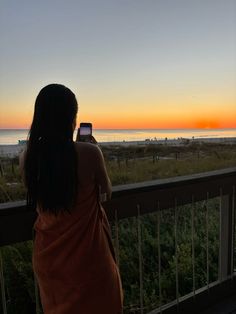 a woman standing on a balcony looking at the sunset