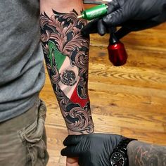 a man with a tattoo on his arm is getting inked by another person in black gloves