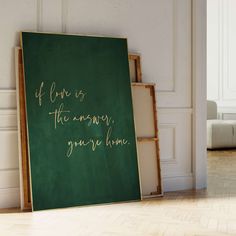 a green chalkboard with gold writing on it in front of a white wall and stairs