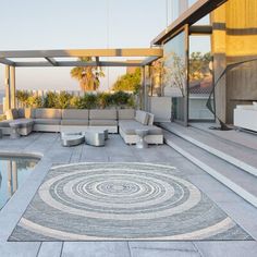 an outdoor area with a pool, couches and rugs on the concrete floor