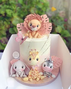 a birthday cake decorated with animals and an animal figurine sitting on top of it