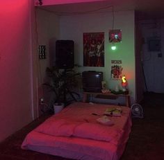 a room with a bed, desk and neon lights on the wall above it is lit up by two lamps