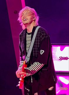 a male in a black and white shirt is holding a red object while standing on stage