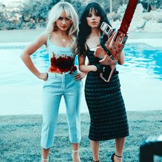 two women standing next to each other in front of a pool holding chainsaws