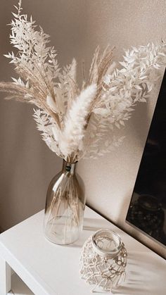 a vase filled with white flowers sitting on top of a table next to a mirror