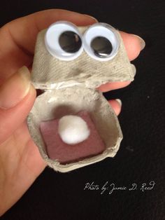 someone is holding an egg carton with googly eyes