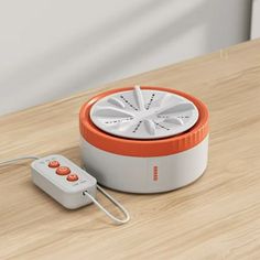 an orange and white speaker sitting on top of a wooden table next to a remote control