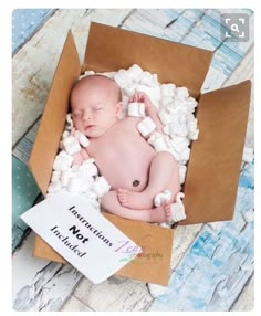 a baby is laying in a box with marshmallows