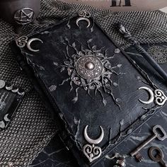 an old book with metal decorations on it sitting on top of a table next to other items