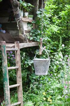 an old ladder is hanging from the side of a house with potted plants on it