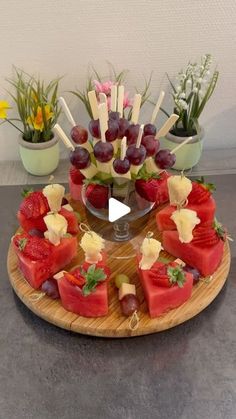 a platter with watermelon, grapes and strawberries arranged on skewers