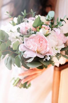 a bride holding a bouquet of pink and white flowers