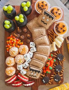 a wooden cutting board topped with crackers and halloween treats on top of a table