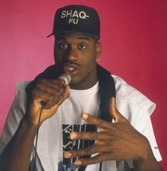 a man holding a microphone in his right hand and wearing a hat with the word shaq fu on it