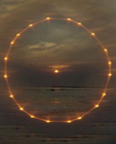 the sun is shining brightly in the sky over the ocean and beach as seen through an orange circle