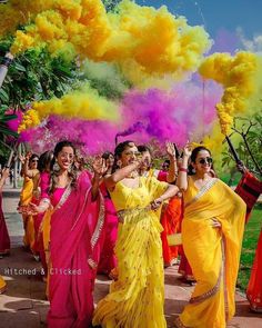 women in sari dancing with colored powder on their faces and arms, all dressed in bright colors