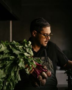 a man in an apron is holding some vegetables