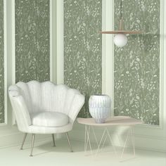 a white chair sitting next to a table with a vase on it in front of a green wallpapered room