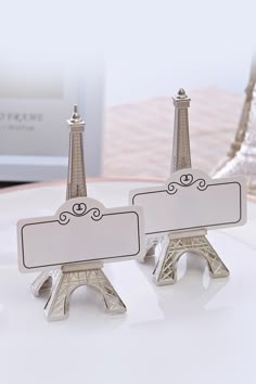 pair of silver eiffel tower place cards on white plate with glass vase in background