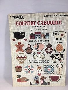 a cross stitch book with pictures of farm animals and sheeps on it's cover