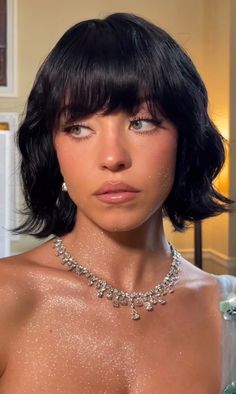 a close up of a person wearing a necklace and dress with glitter on it's chest