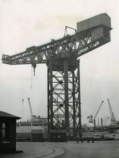 an old black and white photo of a crane in the process of being lifted by cranes