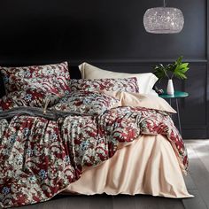 a bed with red and white comforter next to a green plant on a table