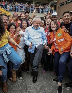 a group of people posing for a photo with an older man in the middle surrounded by other people