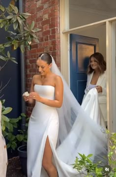 two women in white dresses and one is wearing a veil