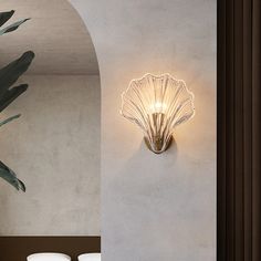 a wall light that is mounted on the side of a wall next to a potted plant