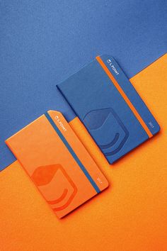 two orange and blue notebooks sitting next to each other on an orange and blue background