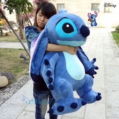 a woman holding a large blue stuffed animal in her arms and hugging it's face