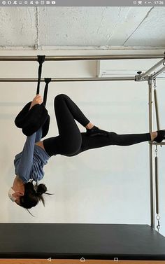 a woman doing aerial acrobatics on a black mat in front of a white wall