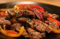 a close up of food on a plate with peppers and meat in the foreground