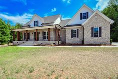 a large brick house sitting on top of a grass covered field in front of trees