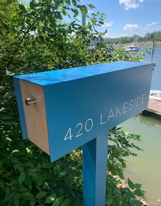 a blue mailbox sitting on the side of a lake