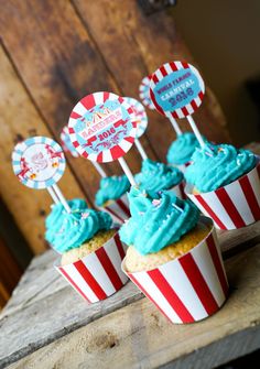 some cupcakes with blue frosting and candy on top are sitting on a table