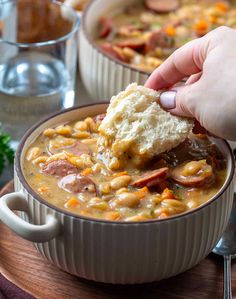 a person is dipping some food into a bowl full of beans and ham chowee