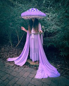 a woman in a purple dress holding an umbrella over her head