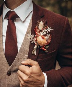 a man wearing a suit and tie with a boutonniere on his lapel